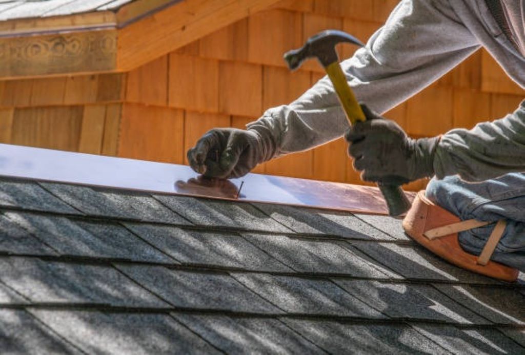 A shingling hammer resting on roof shingles, showing its design for roofing tasks