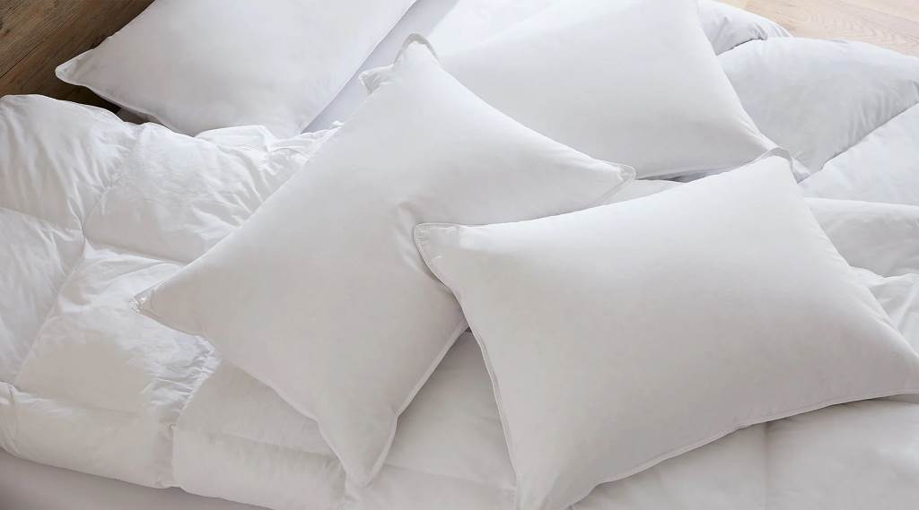 Hand fluffing white Puredown luxury down pillow demonstrating high loft and fill power